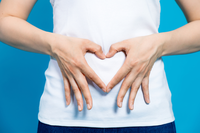 woman making a heart shape with her hands on her stomach to represent gut health