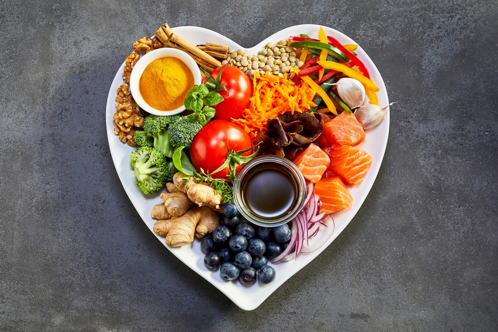 balanced diet of lean protein, healthy fats, veggies, and fruits on heart-shaped plate